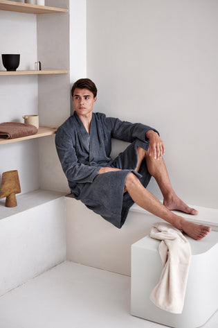 TOLEDO badjas | oceanview een man die op een verhoging zit en een grijze badjas draagt