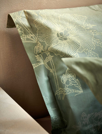 GREEN GIFT dekbedovertrekset | smoke green detail shot van een hoofdkussen in een groene kleur met een overloop en met getekende bloemen en planten erop