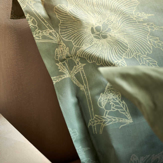 GREEN GIFT dekbedovertrekset | smoke green detail shot van een hoofdkussen in een groene kleur met een overloop en met getekende bloemen en planten erop