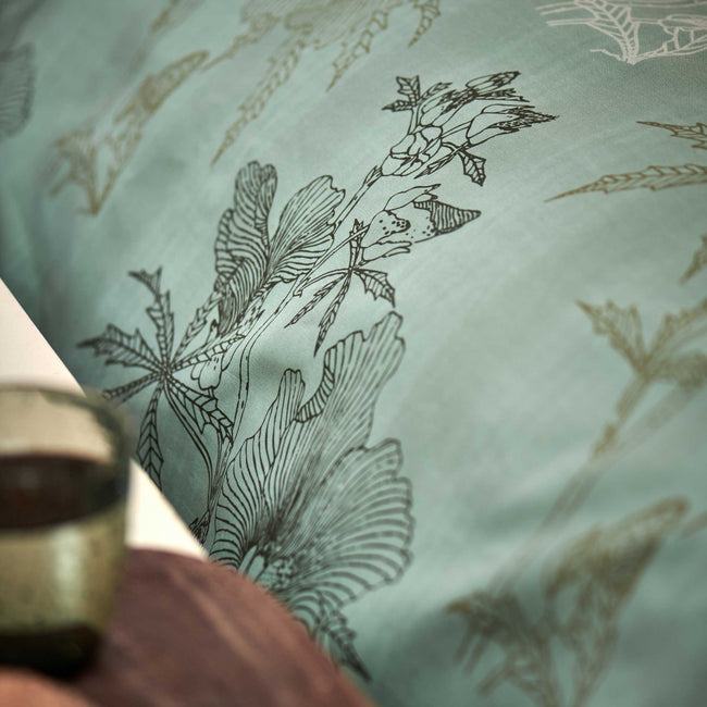 GREEN GIFT dekbedovertrekset | smoke green detail shot van een dekbedovertrek in een groene kleur met een print van bladeren en bloemen