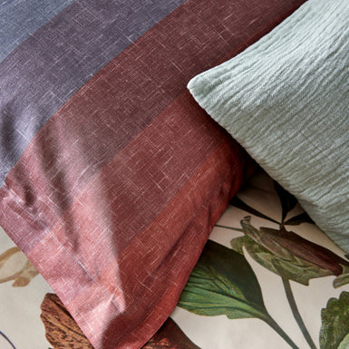 HOLIDAY dekbedovertrekset | cream tan Detail shot van een kussen met strepen in een overloop van blauwe en rode kleuren