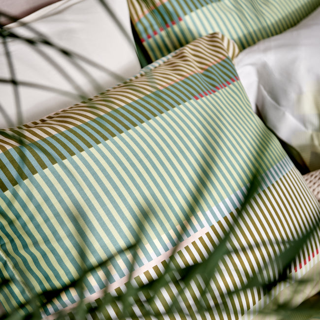 OPTIMIST dekbedovertrekset | smoke green detailshot van een dekbedovertrek met een print van strepen in blauwe, bruine en groene kleuren