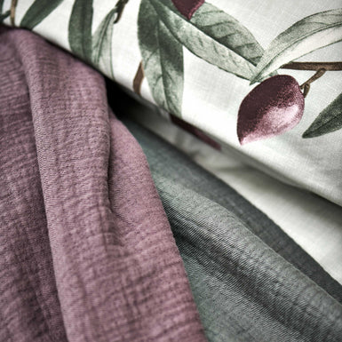 OLIVE dekbedovertrekset | multi detail shot van een hoofdkussen in een lichtgroene kleur met olijftakken en spreien in groene en paarse kleuren