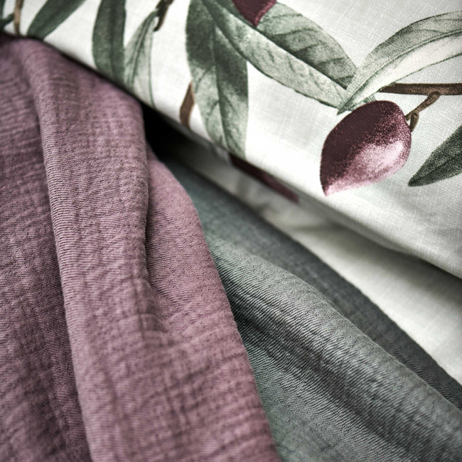 OLIVE dekbedovertrekset | multi detail shot van een hoofdkussen in een lichtgroene kleur met olijftakken en spreien in groene en paarse kleuren