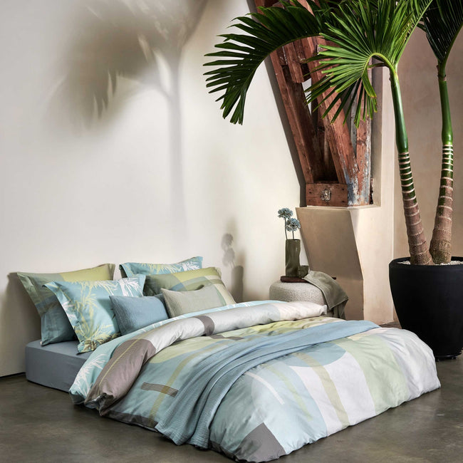 PALM PARADISE dekbedovertrekset | thyme Palm Paradise thyme dekbedovertrek heeft silhouetten van palmbomen in bruin, beige, groen en wit op een lichtblauwe achtergrond. De achterkant van het dekbedovertrek heeft dezelfde print. De kussens hebben aan beide kanten palmbomen.