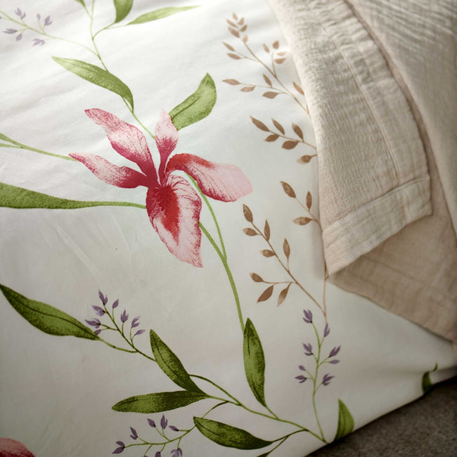 SERENE FLOWER dekbedovertrekset | offwhite detail shot van een wit dekbedovertrek met roze bloemen en groene bladeren en een beige sprei