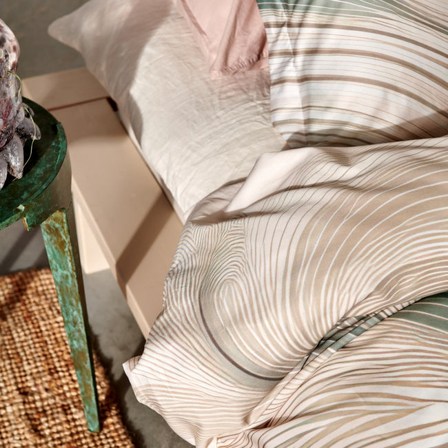 FLOWING dekbedovertrekset | cream tan Detail shot van een dekbedovertrek met beige en groene organische lijnen