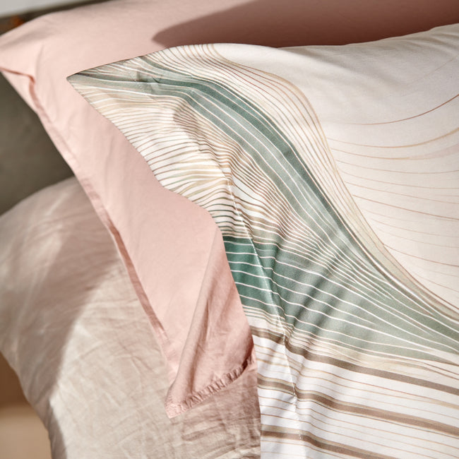 FLOWING dekbedovertrekset | cream tan Detail shot van hoofdkussens met een print van beige en groene organische lijnen