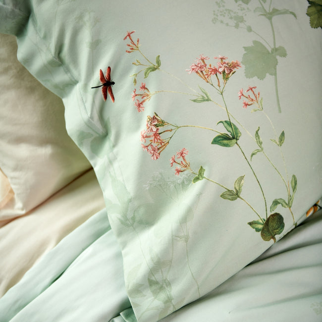 GARDENIA dekbedovertrekset | smoke green detail shot van een lichtgroen kussen met takken en een libelle