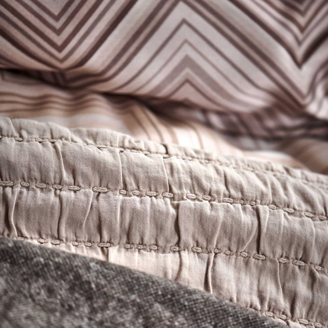 DYNAMIZE dekbedovertrekset | taupe Detail shot van dekbedovertrek en plaids in aarde en bruin tinten