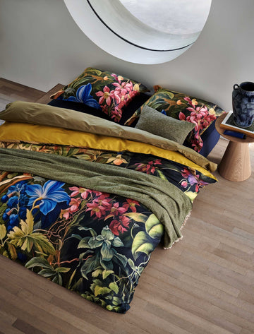 MYSTIC GARDEN dekbedovertrekset | multi Bed in een rustige omgeving Mystic Garden multi dekbedovertrek heeft imposante bloemen in verschillende tinten roze en blauw, omgeven door grote bladeren en struiken. De achterkant van het dekbedovertrek is effen groen/oker