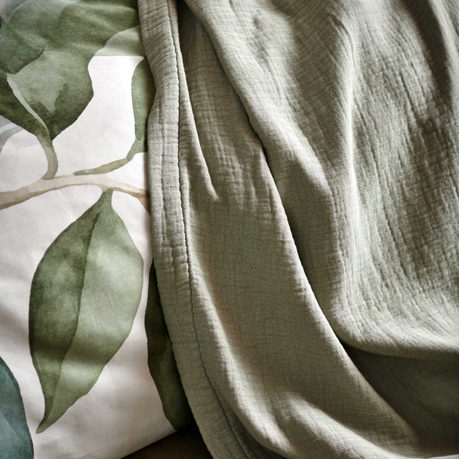GREENSCAPE dekbedovertrekset | thyme detail shot van een plaid in een zacht groene kleur en een dekbedovertrek met groene bladeren