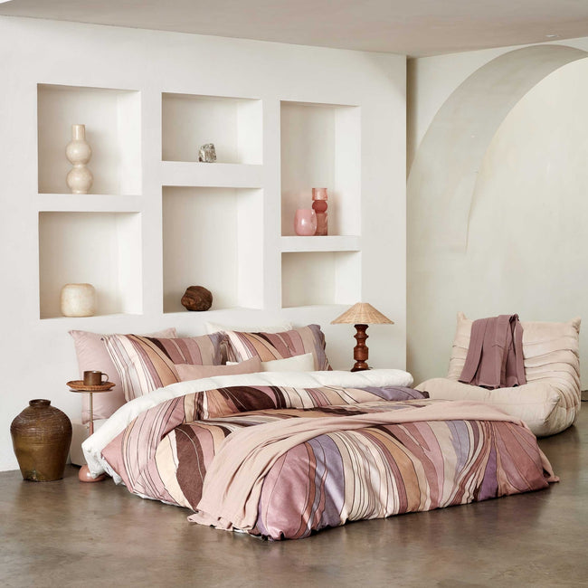 SWIRLS dekbedovertrekset | moonscape Swirls moonscape dekbedovertrek heeft een abstracte versie van een marmerpatroon met paars, roze en bruine tinten. De achterkant van het dekbedovertrek is effen offwhite. De kussens hebben aan beide zijden hetzelfde patroon.