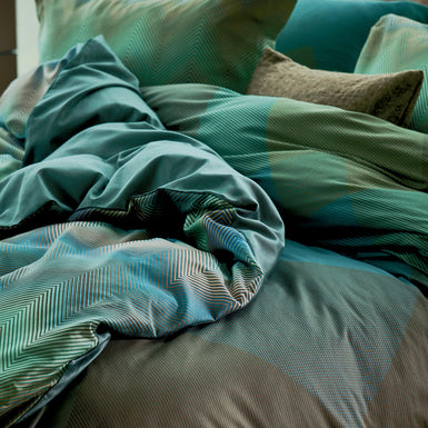 ZIGGY dekbedovertrekset | sage green detail shot van een bed met grafische dekbedovertrekken in groene en blauwe kleuren