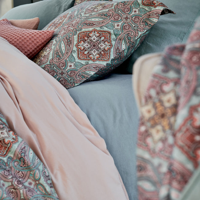 CHARM dekbedovertrekset | pearl blue detail shot van een bed met een paisley dekbedovertrek in blauwe en roze kleuren