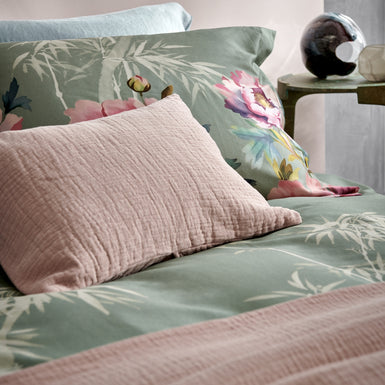 PINK PEONY dekbedovertrekset | multi detail shot van een bed met een dekbedovertrek in een groene kleur met roze bloemen en bamboe takken en een roze kussen