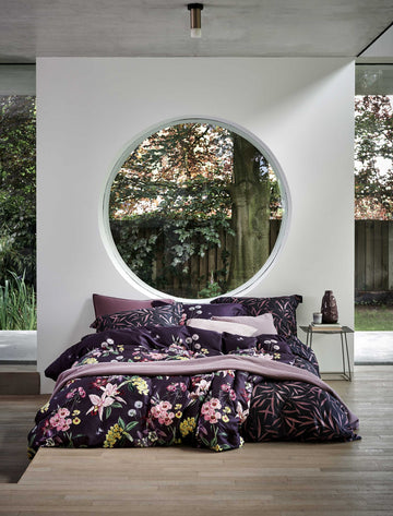 NOIR GARDEN dekbedovertrekset | multi Een bed met een dekbedovertrek met bloemen en bladeren in paarse kleuren