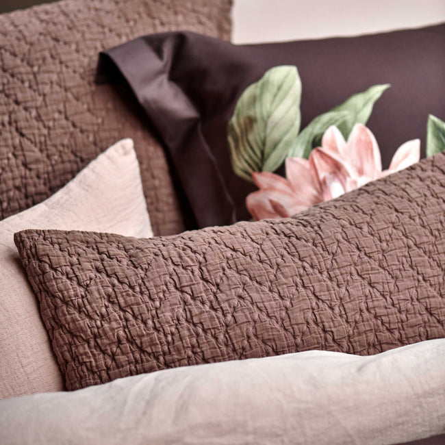 PARADISE BLOOM dekbedovertrekset | dark chocolate detail shot van sierkussens in een bruine kleur en een dekbedovertrek en kussens in bruine en roze kleuren