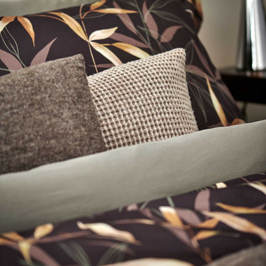 ZEN GARDEN dekbedovertrekset | dark chocolate detail shot van een bruin dekbedovertrek met bamboe takken en kussens in bruien en beige tinten