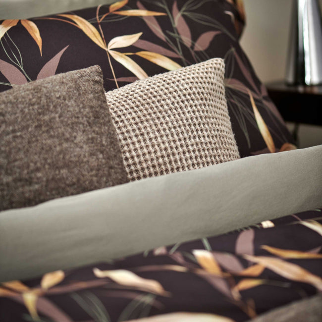 ZEN GARDEN dekbedovertrekset | dark chocolate detail shot van een bruin dekbedovertrek met bamboe takken en kussens in bruien en beige tinten