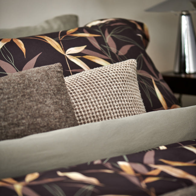 ZEN GARDEN XL dekbedovertrekset | dark chocolate Detail shot van een dekbedovertrek in bruin en groen met een wollen kussen