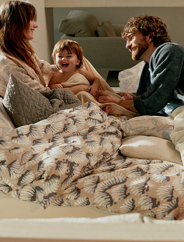 WAKE UP dekbedovertrekset | linen Een lachend stel in bed met een kind op een mooie zonnige ochtend