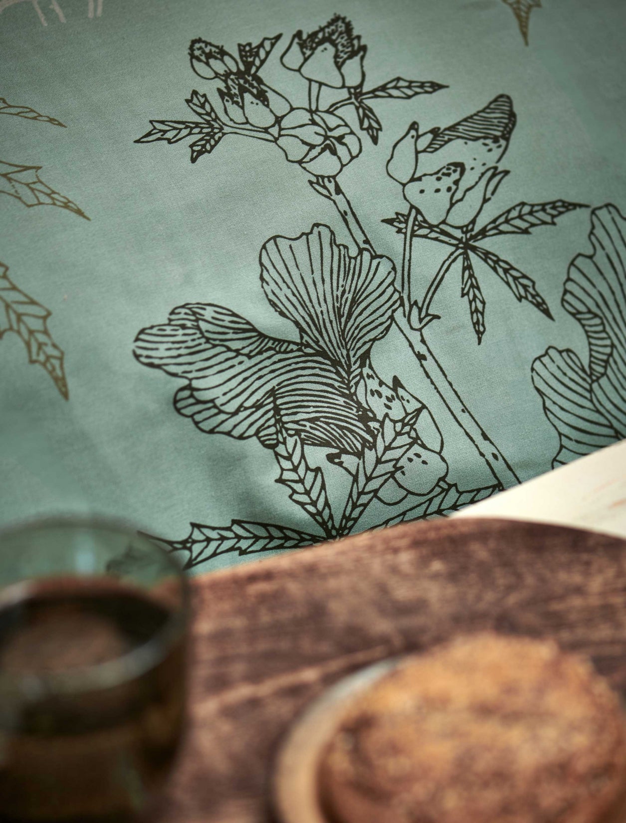 detail shot van een dekbedovertrek met een groene kleur met een zwarte opdruk van bloemen en bladeren