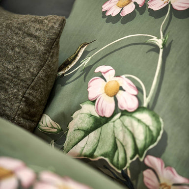 detail shot van een hoofdkussen in een groene kleur met een print van vogels en bloemen