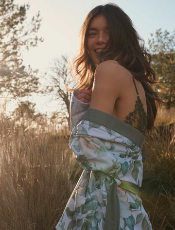 SOFIA badjas | thyme Sofia thyme badjas heeft grote bloemen met creme en groene tinten met groene bladeren op een off white achtergrond. De basjas heeft grote steekzakken, een brede revers en wordt gesloten met een ceintuur in een lijfgroene tint.