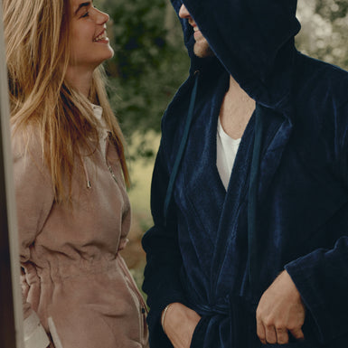 een vrouw die een paarse badjas draagt en een man die een blauwe badjas draagt met een capuchon 