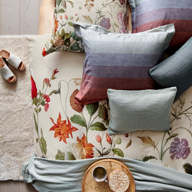top shot van een dekbedovertrek in creme kleur met prachtige bloemen en een design met strepen in een mooie overloop van blauwe en rode kleuren