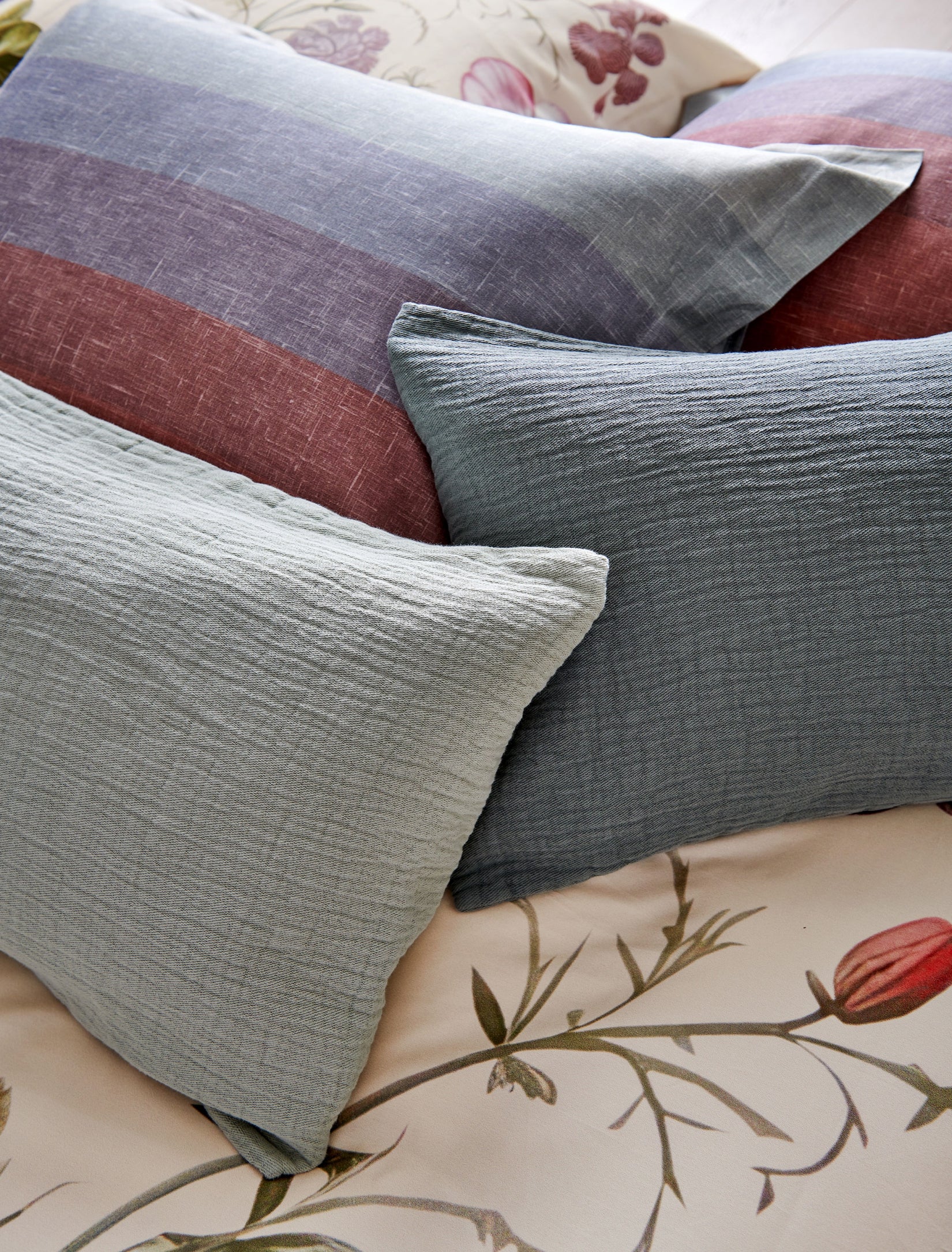 Detail shot van blauwe kussens op een bed met een kussen met strepen in een overloop van blauwe en rode kleuren