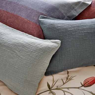 Detail shot van blauwe kussens op een bed met een kussen met strepen in een overloop van blauwe en rode kleuren