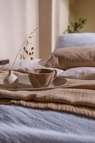 PURE 68 sprei | powder blue detail shot van een bed met een kopje thee in een rustige sfeer