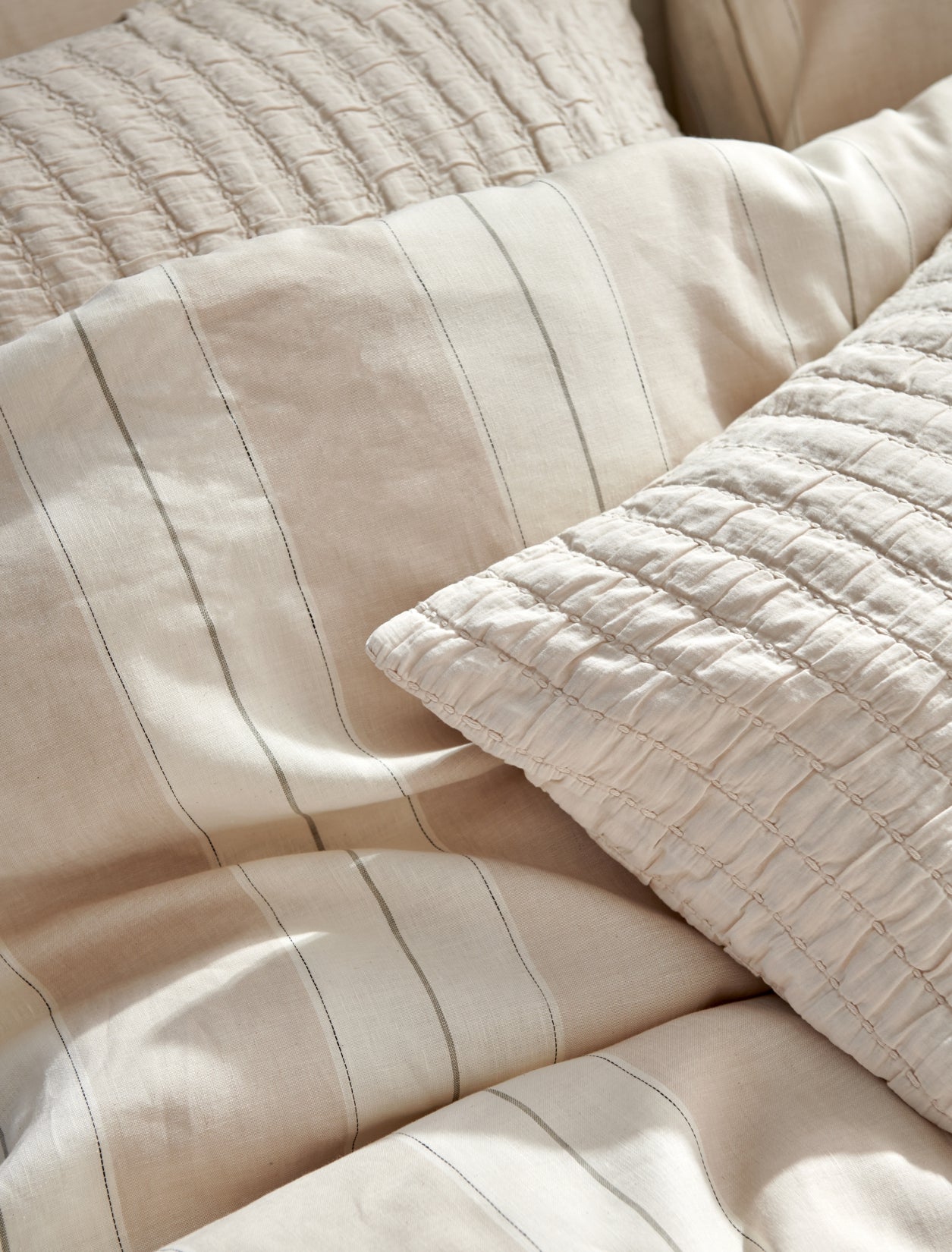 detail shot van een dekbedovertrek in beige tonen met strepen