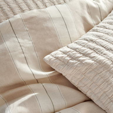 detail shot van een dekbedovertrek in beige tonen met strepen