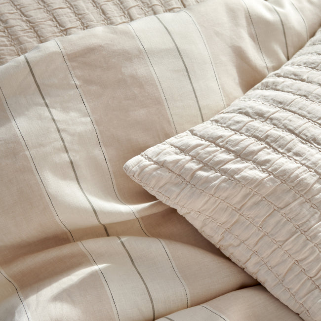 detail shot van een dekbedovertrek in beige tonen met strepen