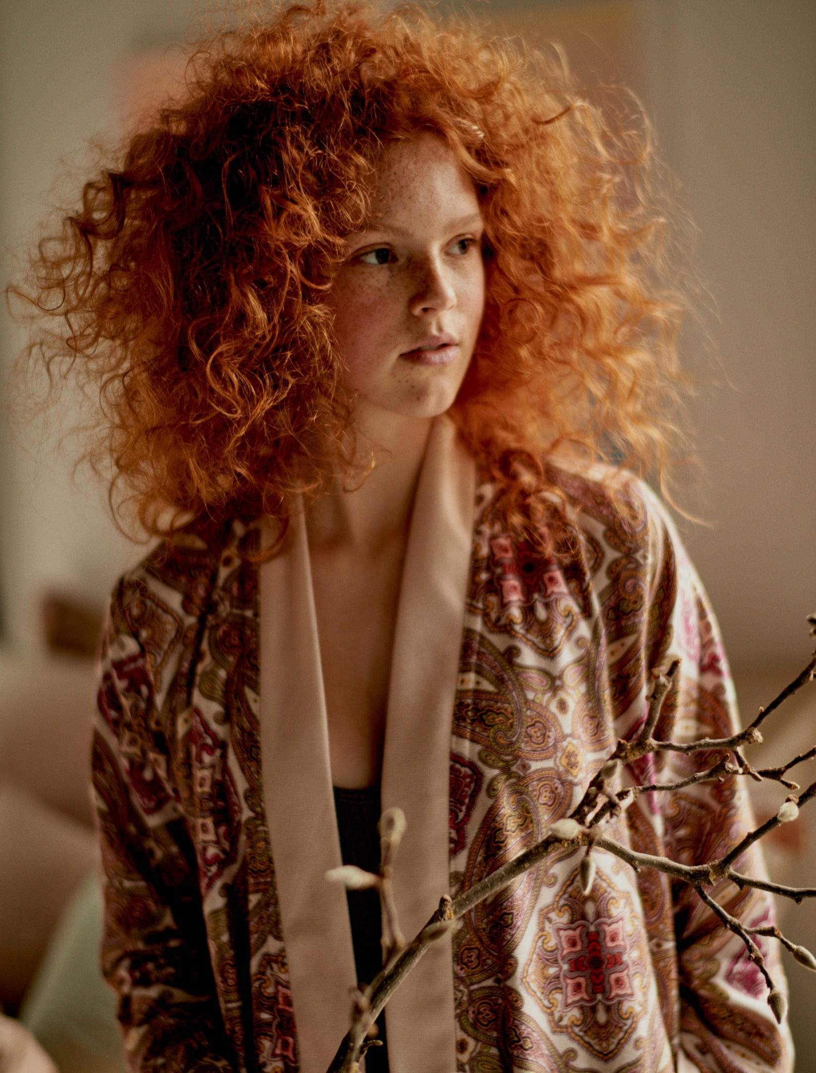 meisje met oranje haren in een badjas met oranje tinten en een paisley print