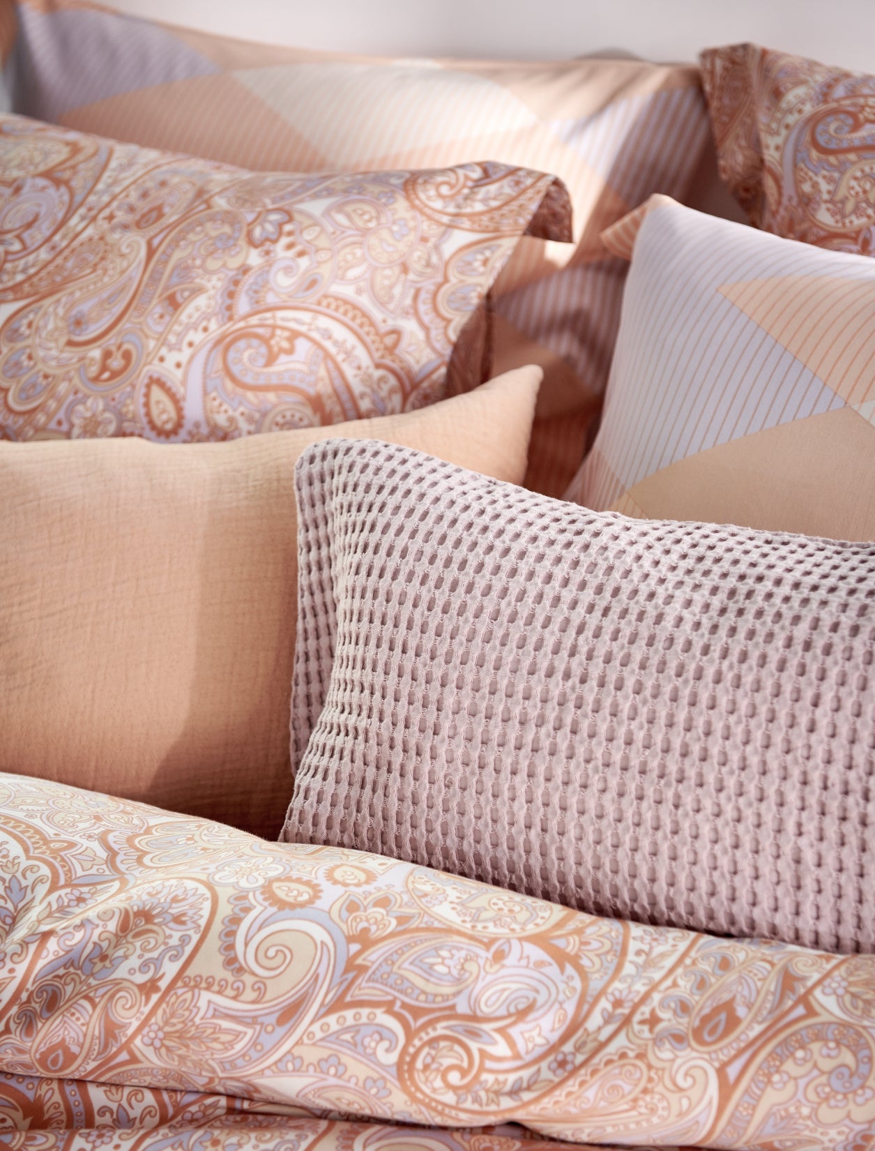 detail shot van kussens op een bed met oranje en paarse pastel kleuren