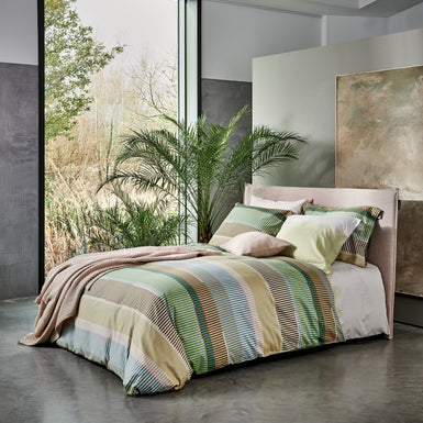 bed in een rustige setting met een groen dekbedovertrek met strepen in bruine en blauwe kleuren