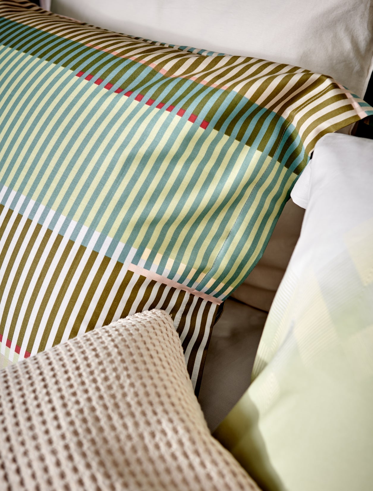 detail shot van een kussen met een print van strepen in groene, blauwe en bruine tinten