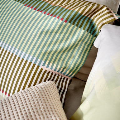 detail shot van een kussen met een print van strepen in groene, blauwe en bruine tinten