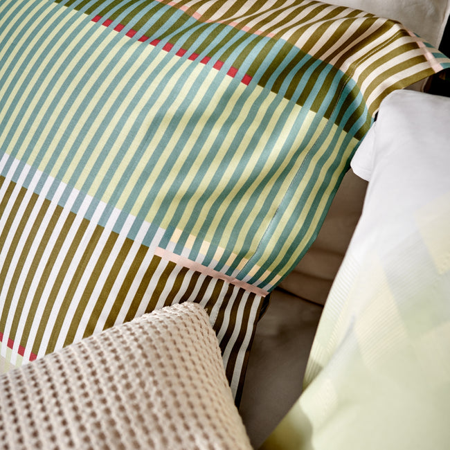 detail shot van een kussen met een print van strepen in groene, blauwe en bruine tinten