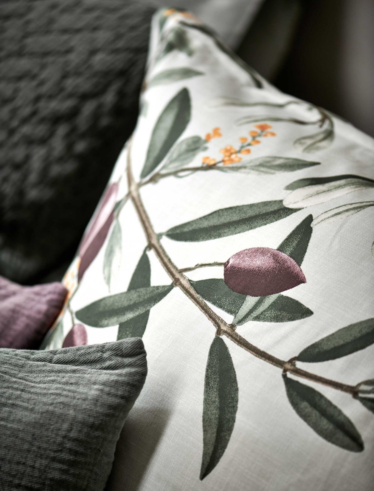 detail shot van een hoofdkussen in een lichtgroene kleur met een print van olijftakken