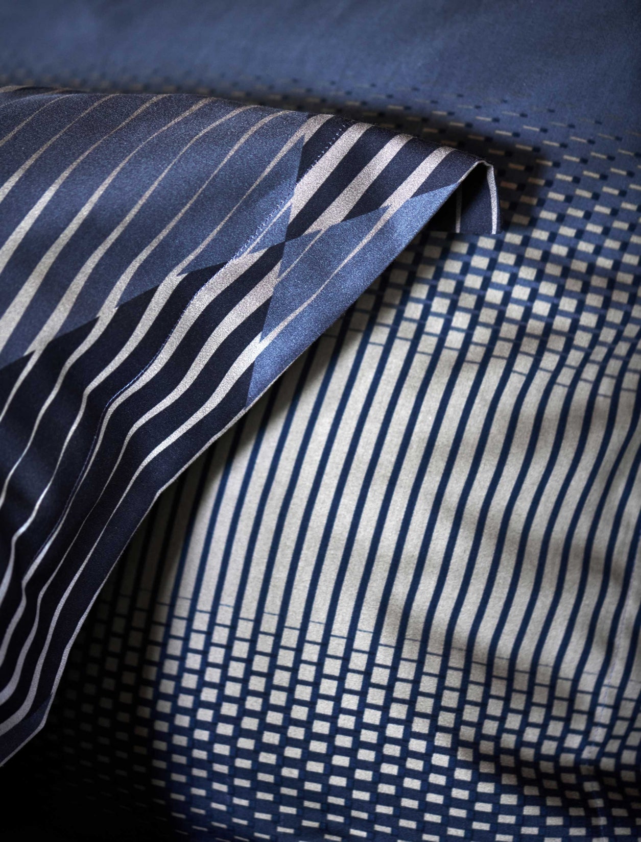 detail shot van een hoofdkussen met grafische print in grijze en donkerblauwe kleuren