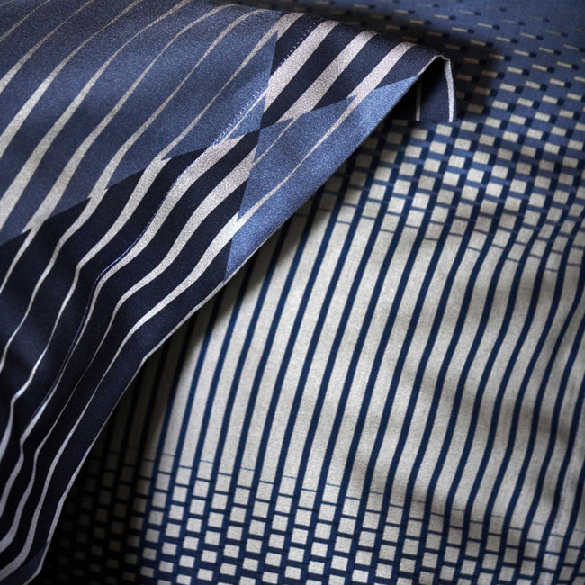 detail shot van een hoofdkussen met grafische print in grijze en donkerblauwe kleuren
