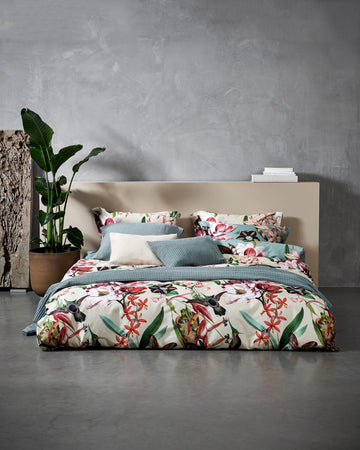 Bed met een overtrekset in beige en blauwe kleur met bloemen, vogels en vlinders in een rustige omgeving