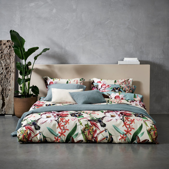 Bed met een overtrekset in beige en blauwe kleur met bloemen, vogels en vlinders in een rustige omgeving