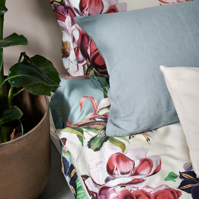 detail shot van een dekbedovertrek in een beige kleur met bloemen en een kussen in een blauwe kleur