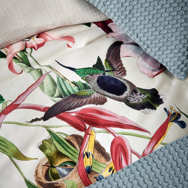detail shot van een dekbedovertrek met bloemen en vogels met een beige achtergrondkleur